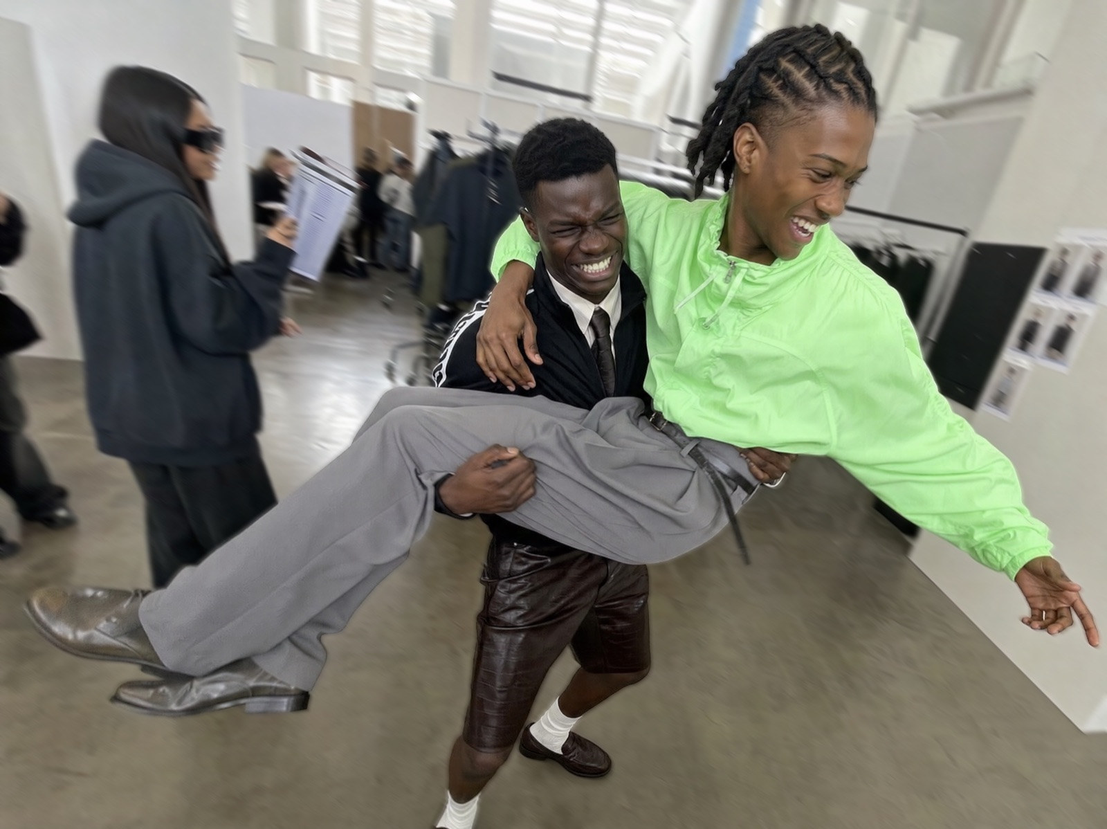 Two people laughing as one lifts the other in a bright studio