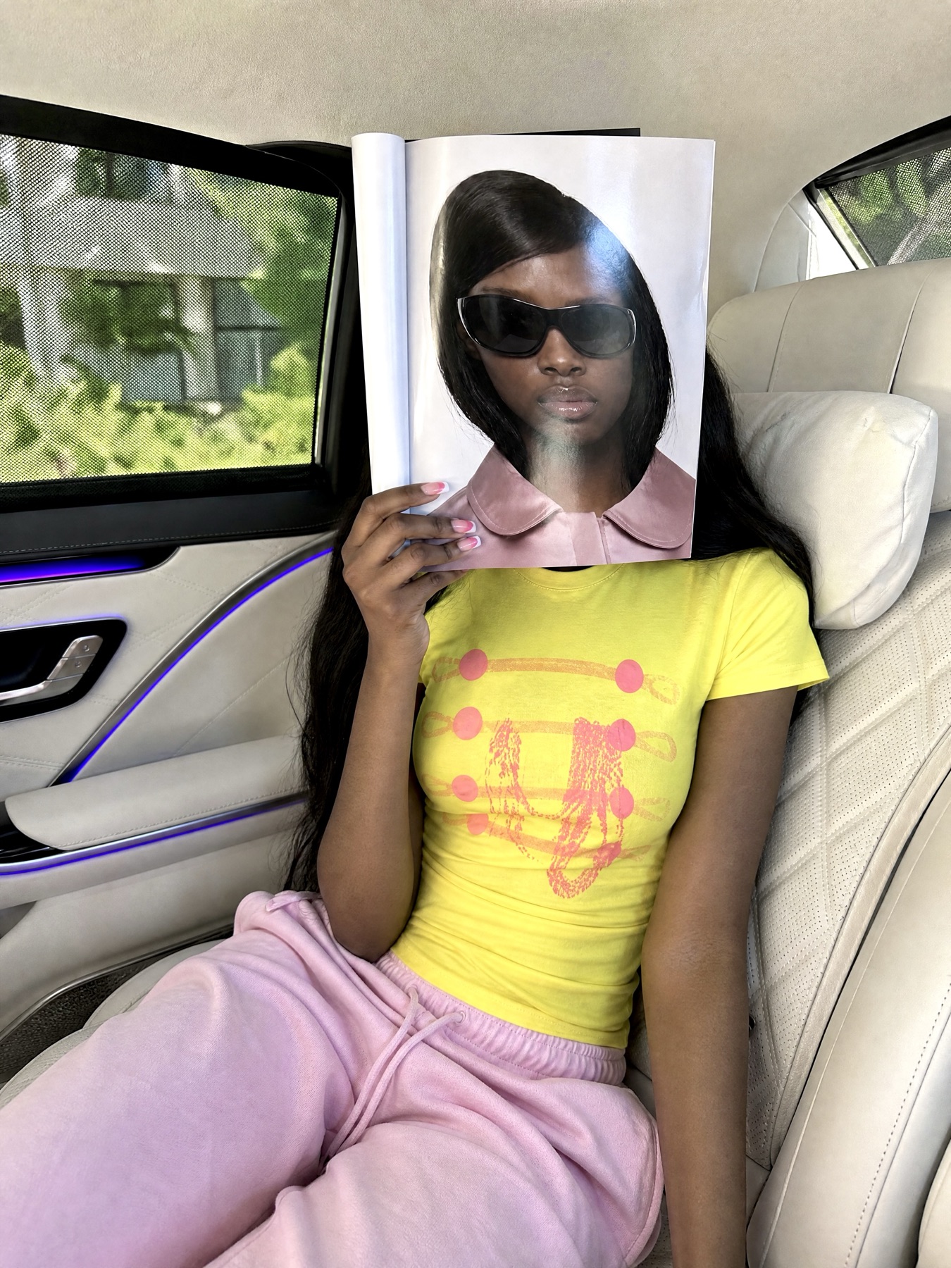 Passenger in a car holding an open magazine over their face